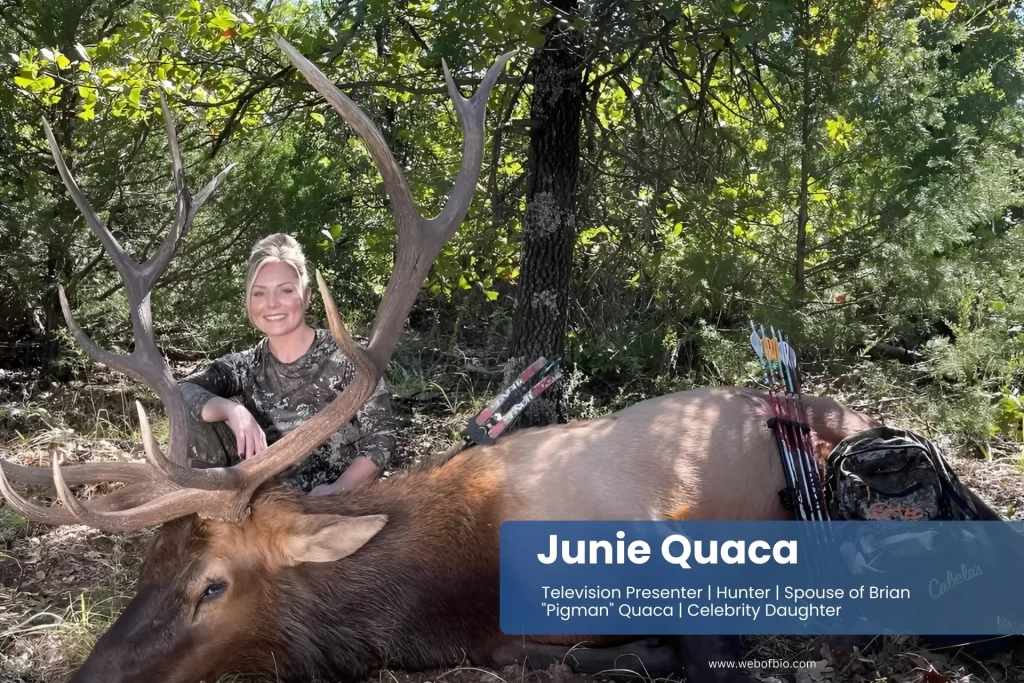 Junie Quaca kneeling next to an elk in the woods.