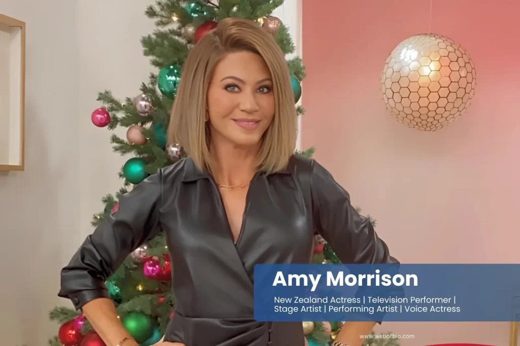 Amy Morrison in a black dress standing in front of a Christmas tree.