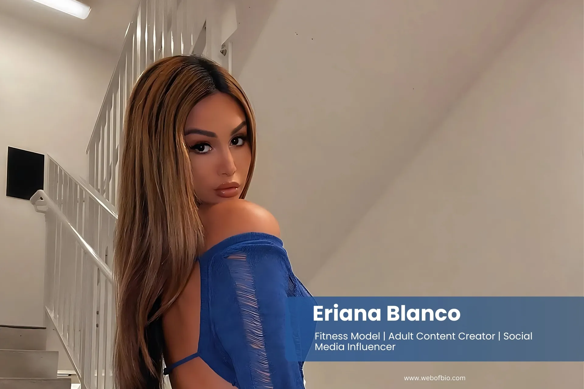 Eriana Blanco in a blue dress posing on the stairs.