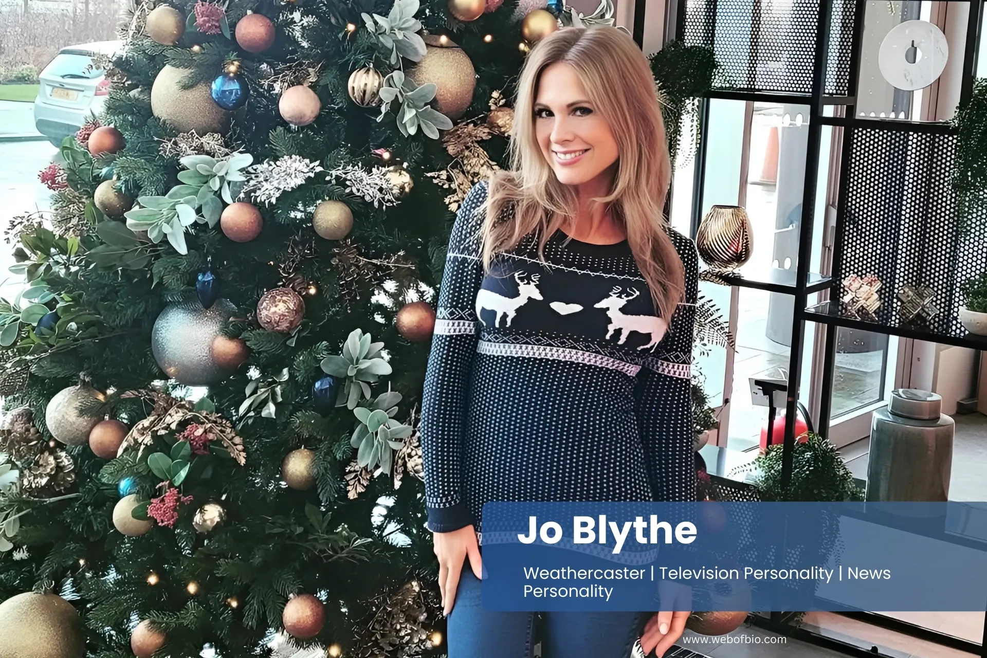Jo Blythe standing in front of a Christmas tree wearing a sweater and boots.