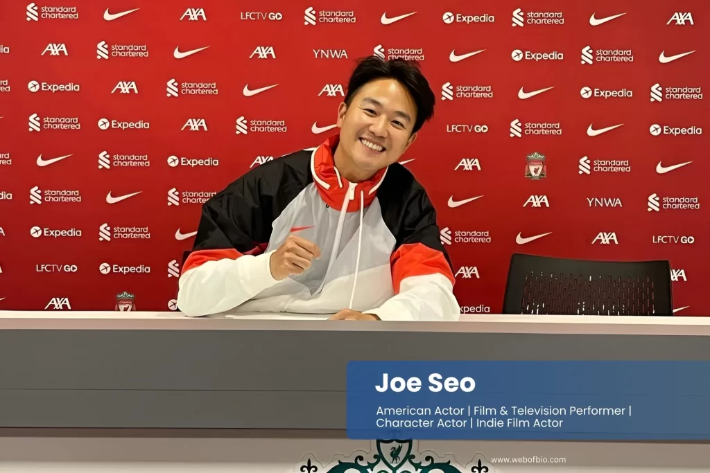 Joe Seo Korean player of Liverpool FC in action, wearing the team's red kit, with a cheering crowd in the stadium behind him.