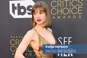 Katja Herbers in a gold dress posing on the red carpet.