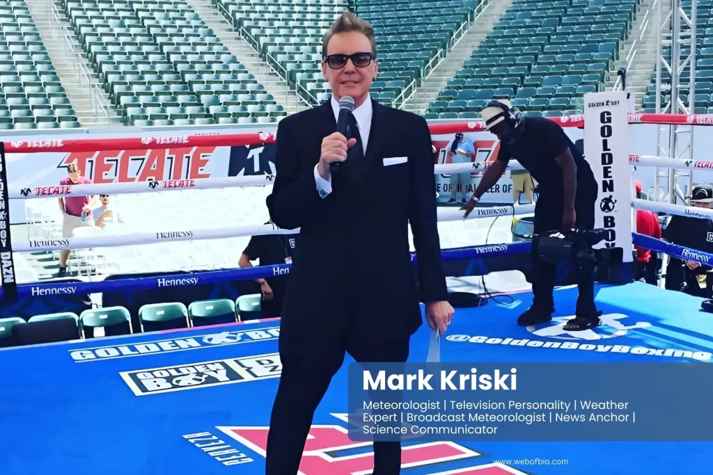 Mark Kriski in a suit and tie standing in front of a boxing ring.