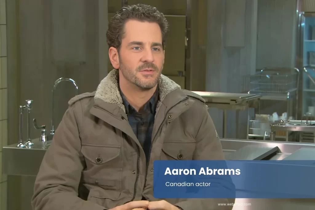 Aaron Abrams wearing jacket sitting comfortably in chair.
