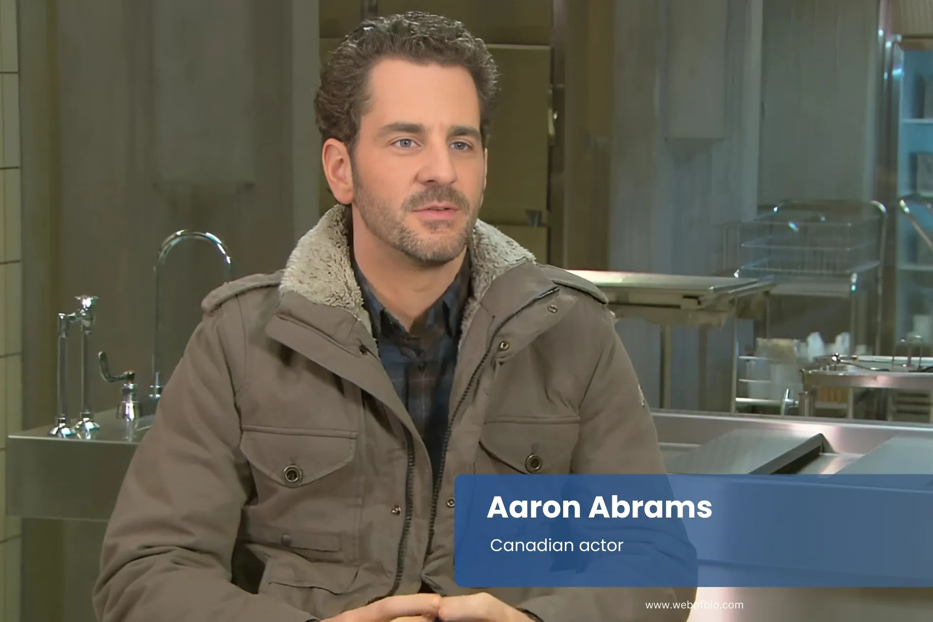 Aaron Abrams wearing jacket sitting comfortably in chair.
