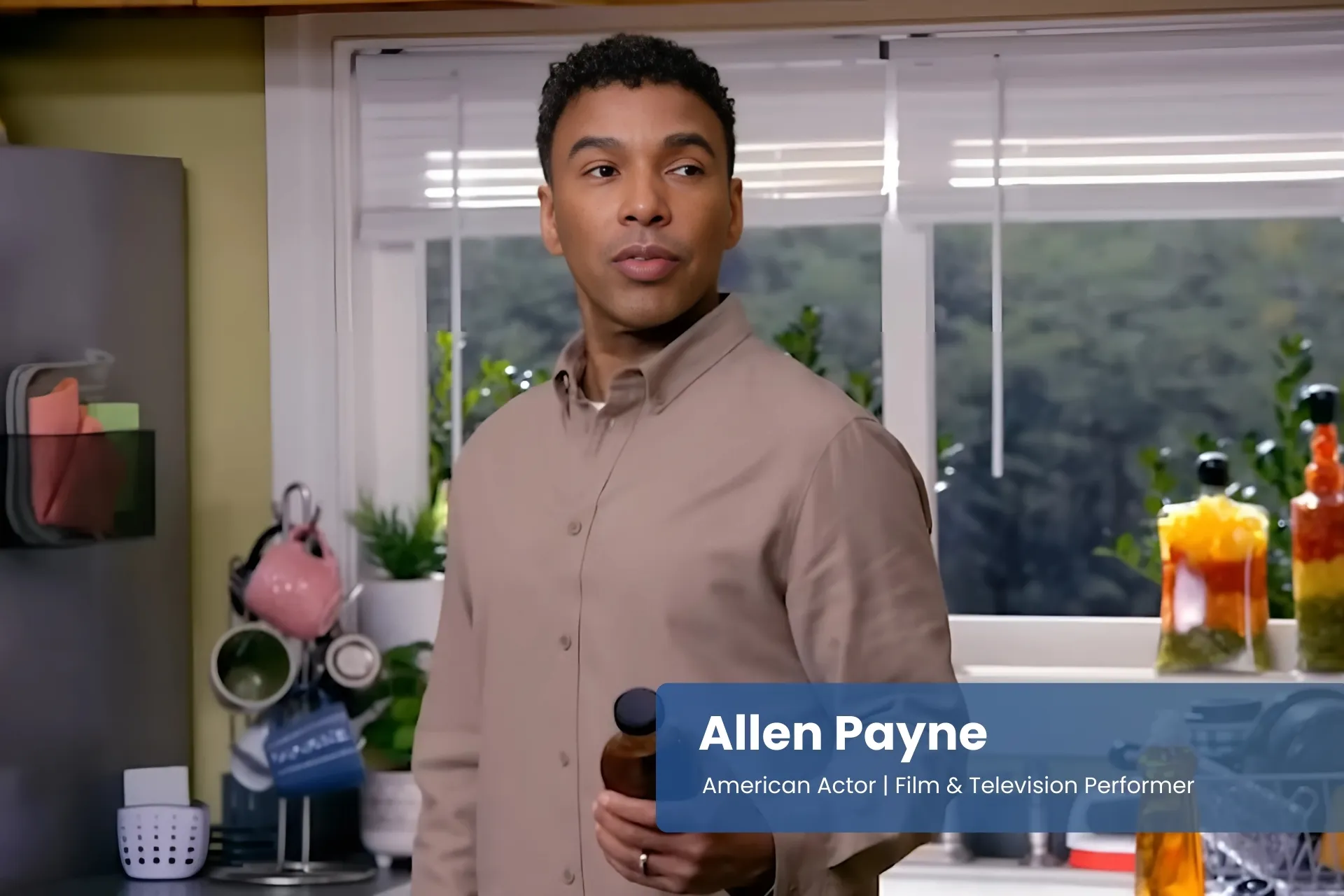 Allen Payne standing in a kitchen holding a bottle.