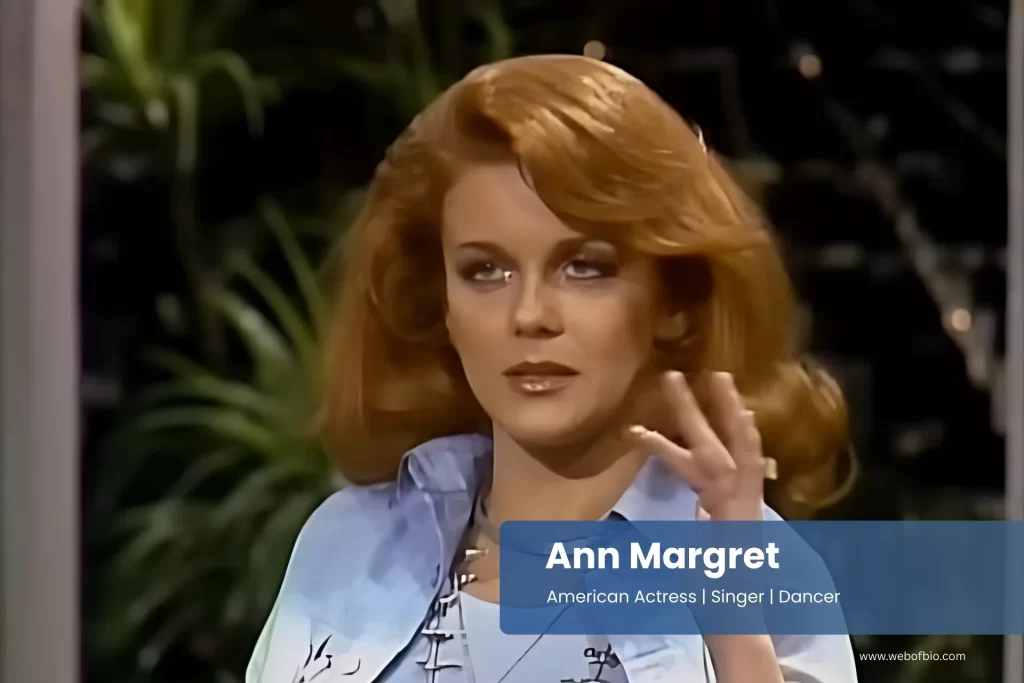 Ann Margret with red hair and a blue shirt.