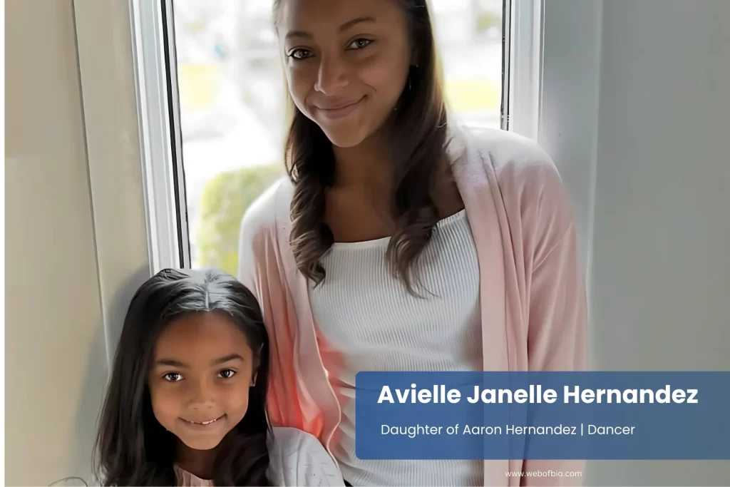 Avielle Janelle Hernandez and her mother smiling while standing together in front of a large window, with natural light illuminating the scene.