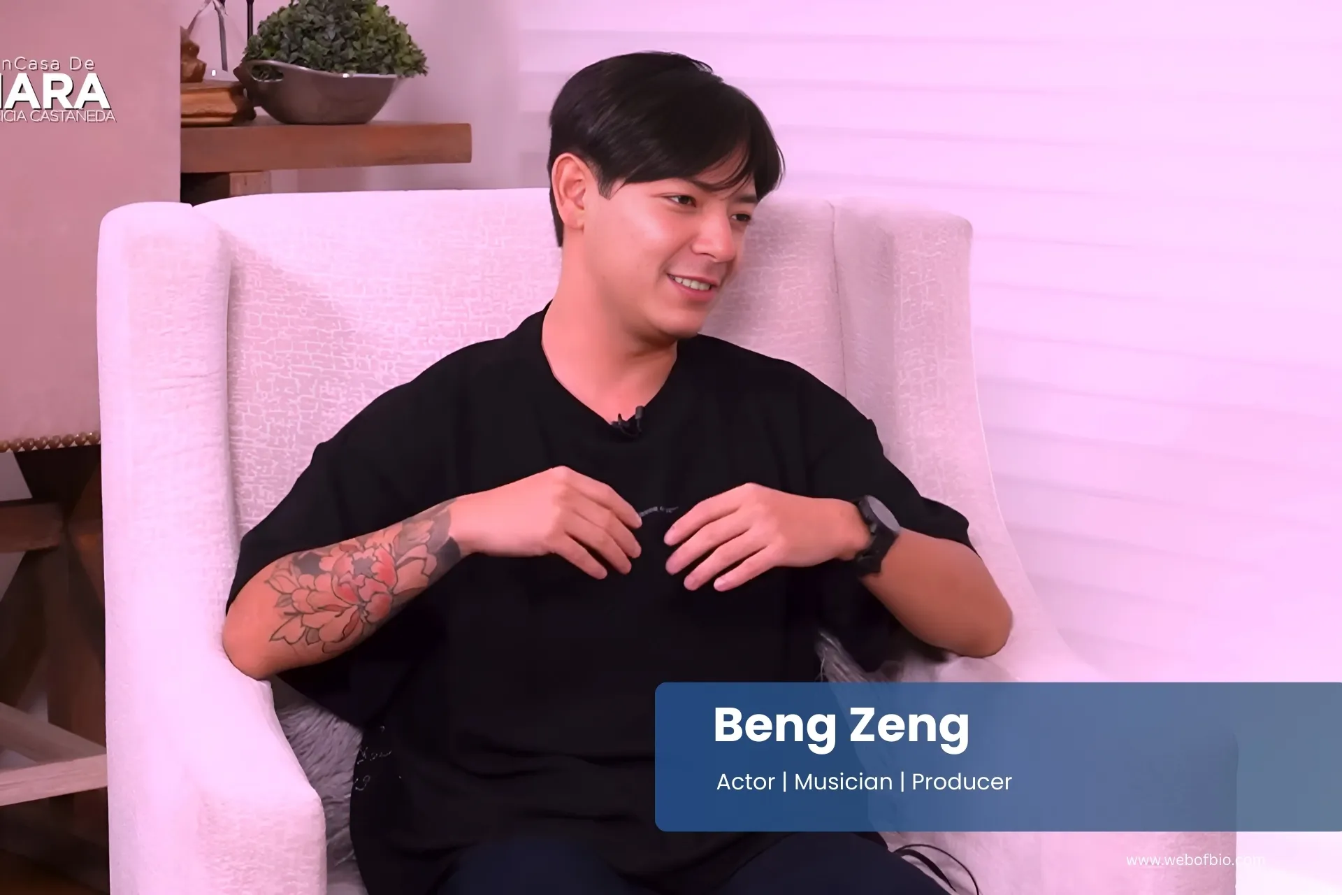 Beng Zeng sitting in a chair with tattoos on their arm.