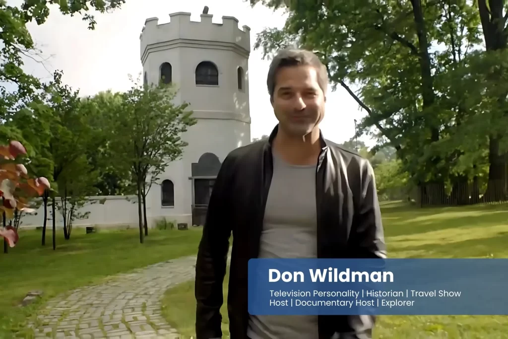 Don Wildman in a leather jacket standing in front of a castle.