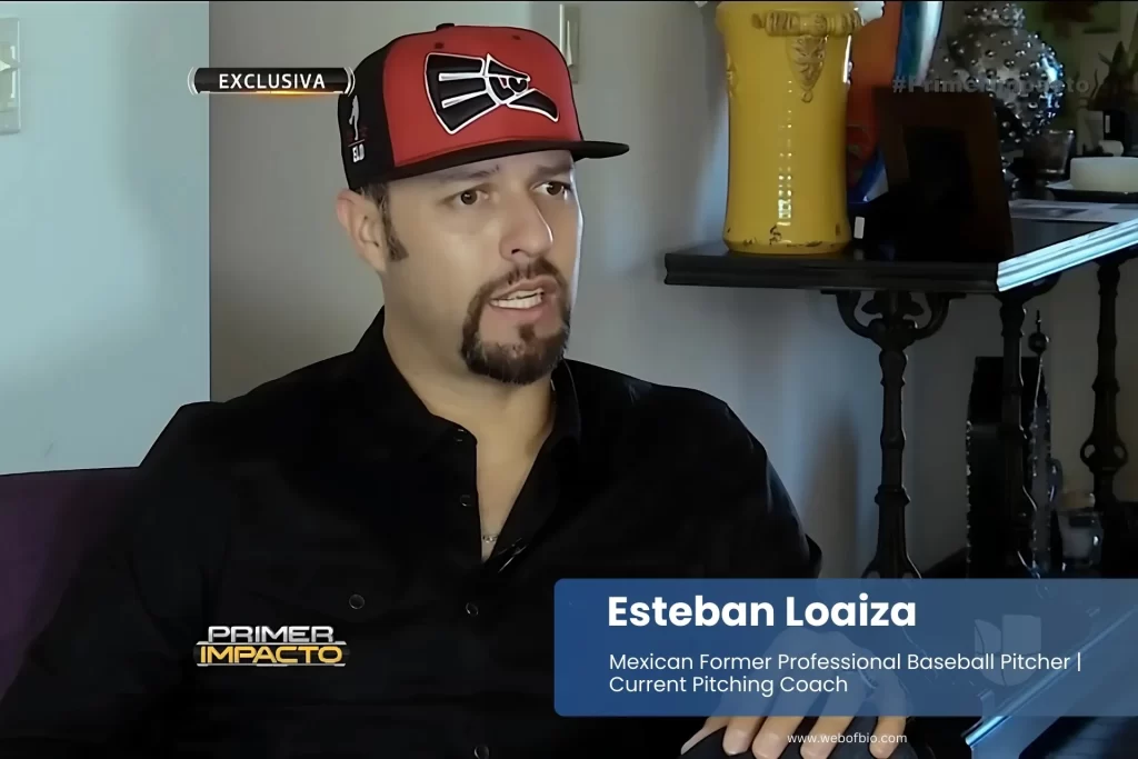 Esteban Loaiza sitting on couch wearing red hat and black shirt.