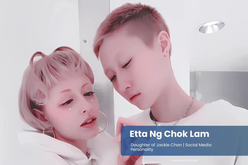 Etta Ng Chok Lam and his wife Andi Autumn, with pink hair, are smiling and taking selfies together in a vibrant outdoor setting.