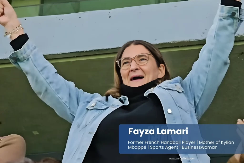 Fayza Lamari enthusiastically cheering in blue jacket and jeans.