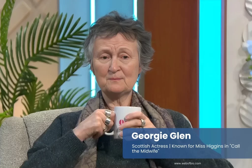 Georgie Glen relaxing in chair holding coffee cup.