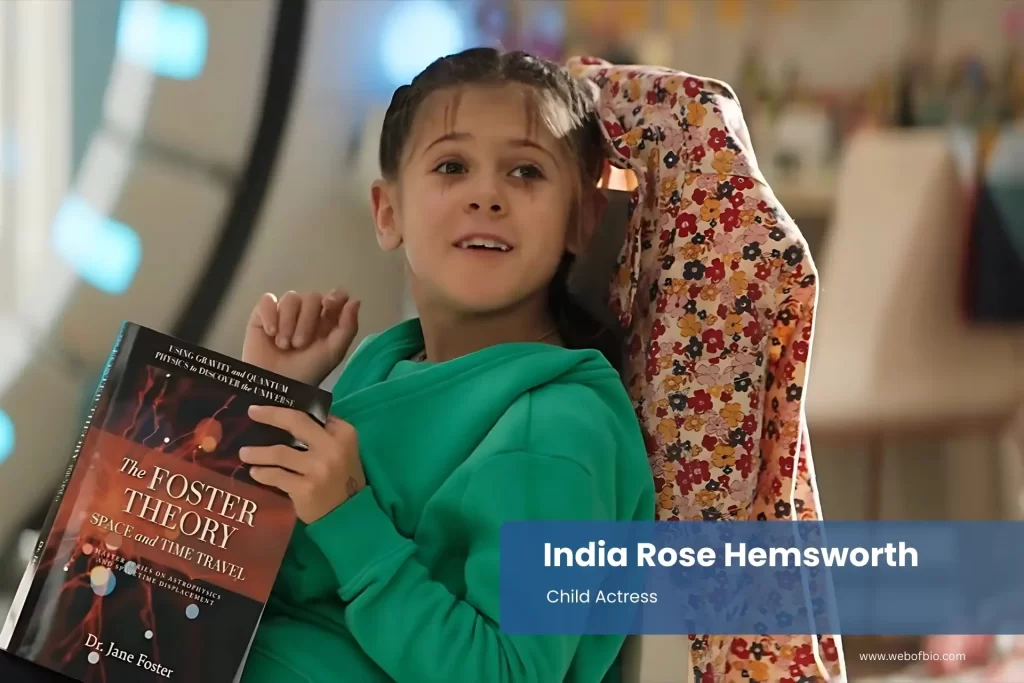 India Rose Hemsworth sitting in a chair holding a book.