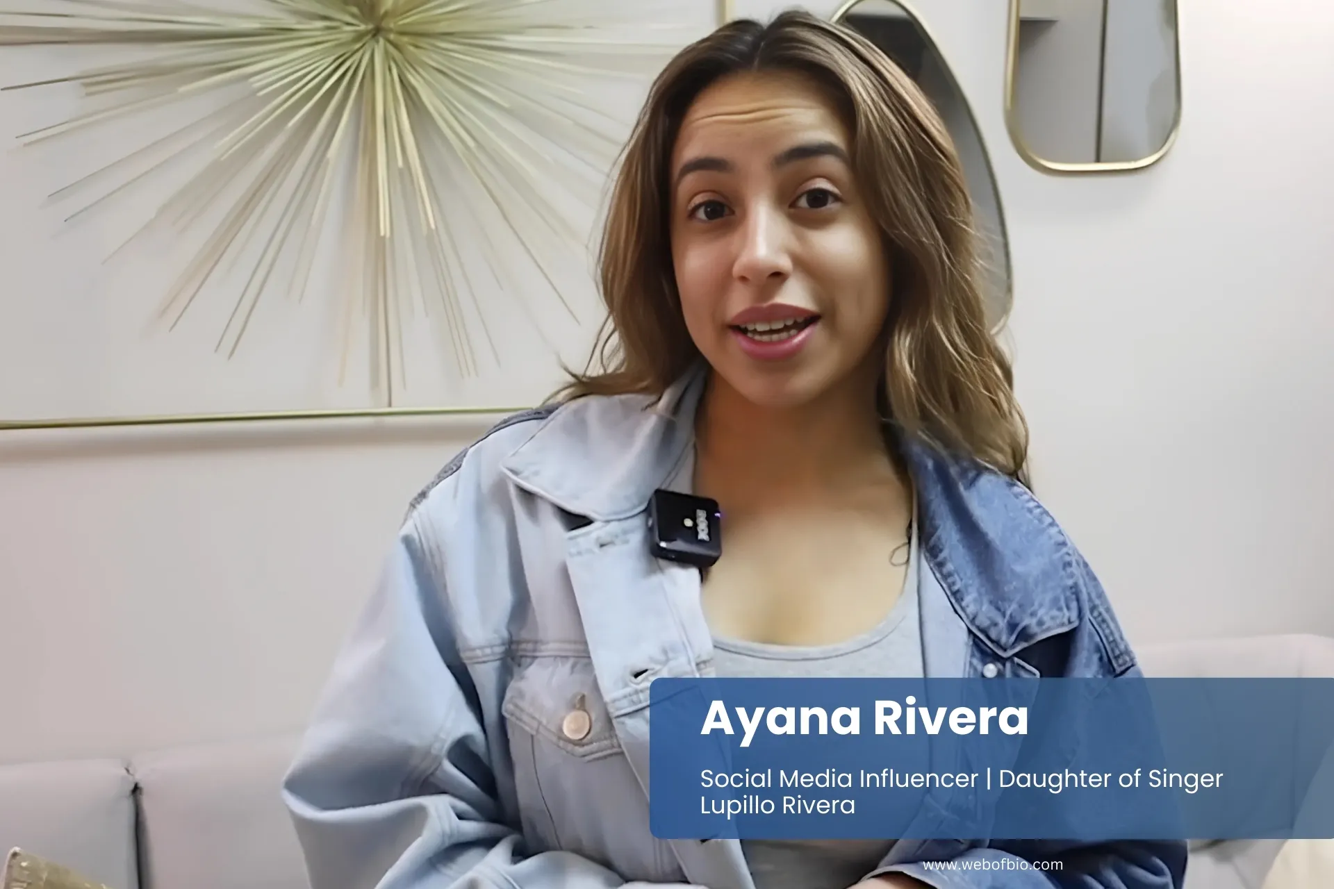 Ayana Rivera in denim jacket standing in front of stylish couch.