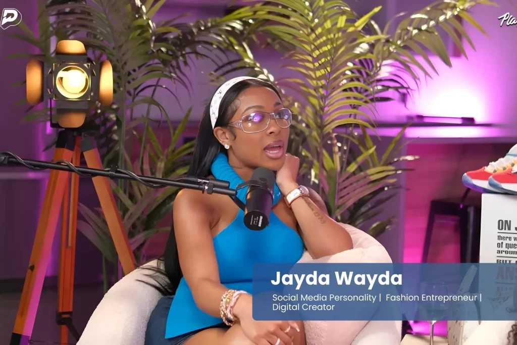 Jayda Wayda is sitting on a chair with a microphone in front of them.