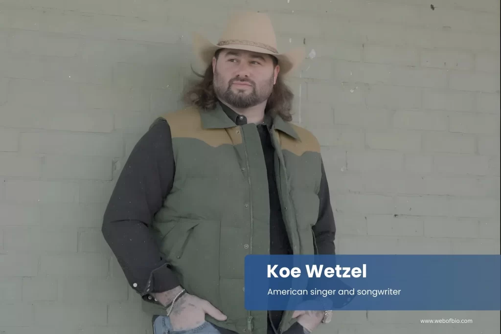 Koe Wetzel in a cowboy hat leaning against a brick wall
