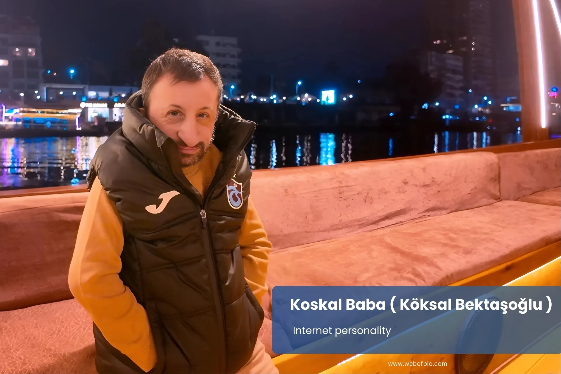 Koskal Baba on a boat at night, surrounded by calm water and illuminated by soft moonlight.