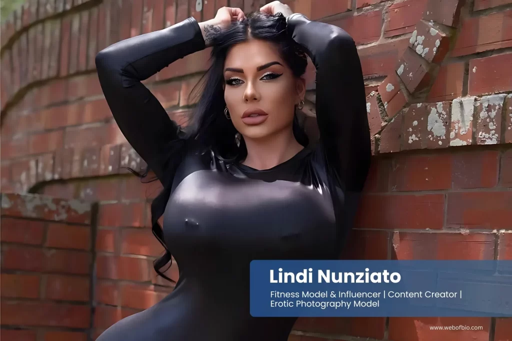 Lindi Nunziato in a black suit leaning against a brick wall.