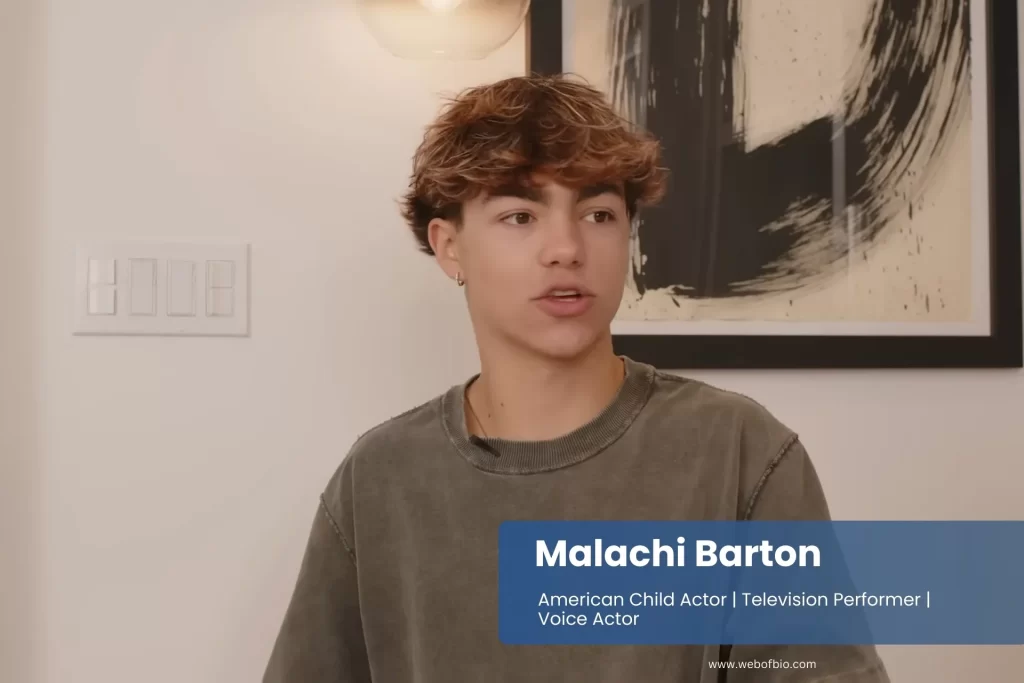 Malachi Barton with curly hair is seated in a cozy room.