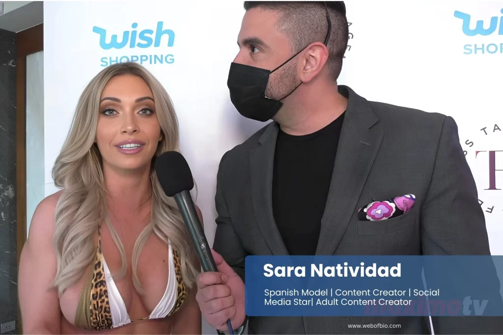 A man wearing a mask stands beside Sara Natividad in a bikini.