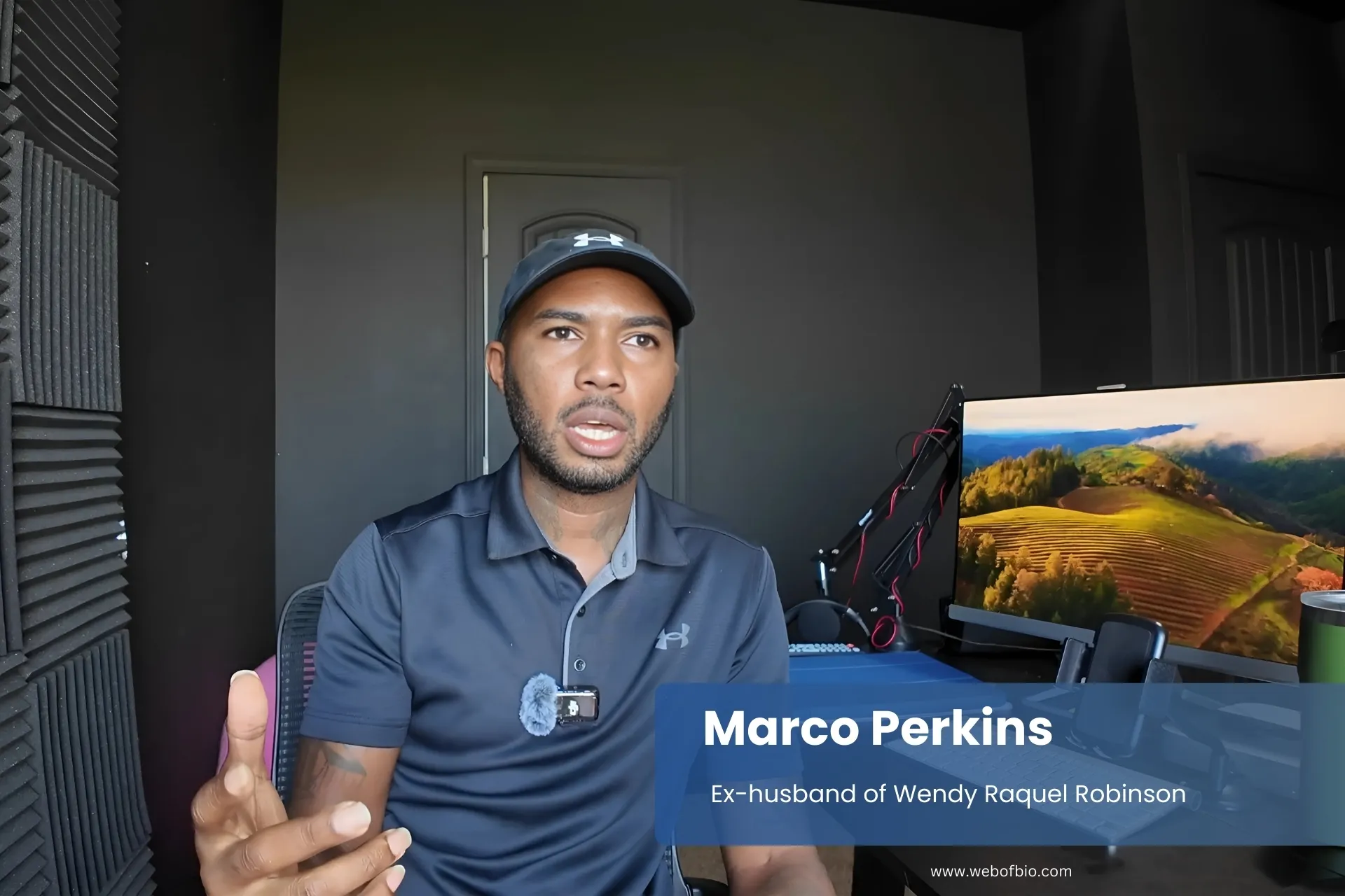 Marco Perkins wearing a black shirt sits at a desk.