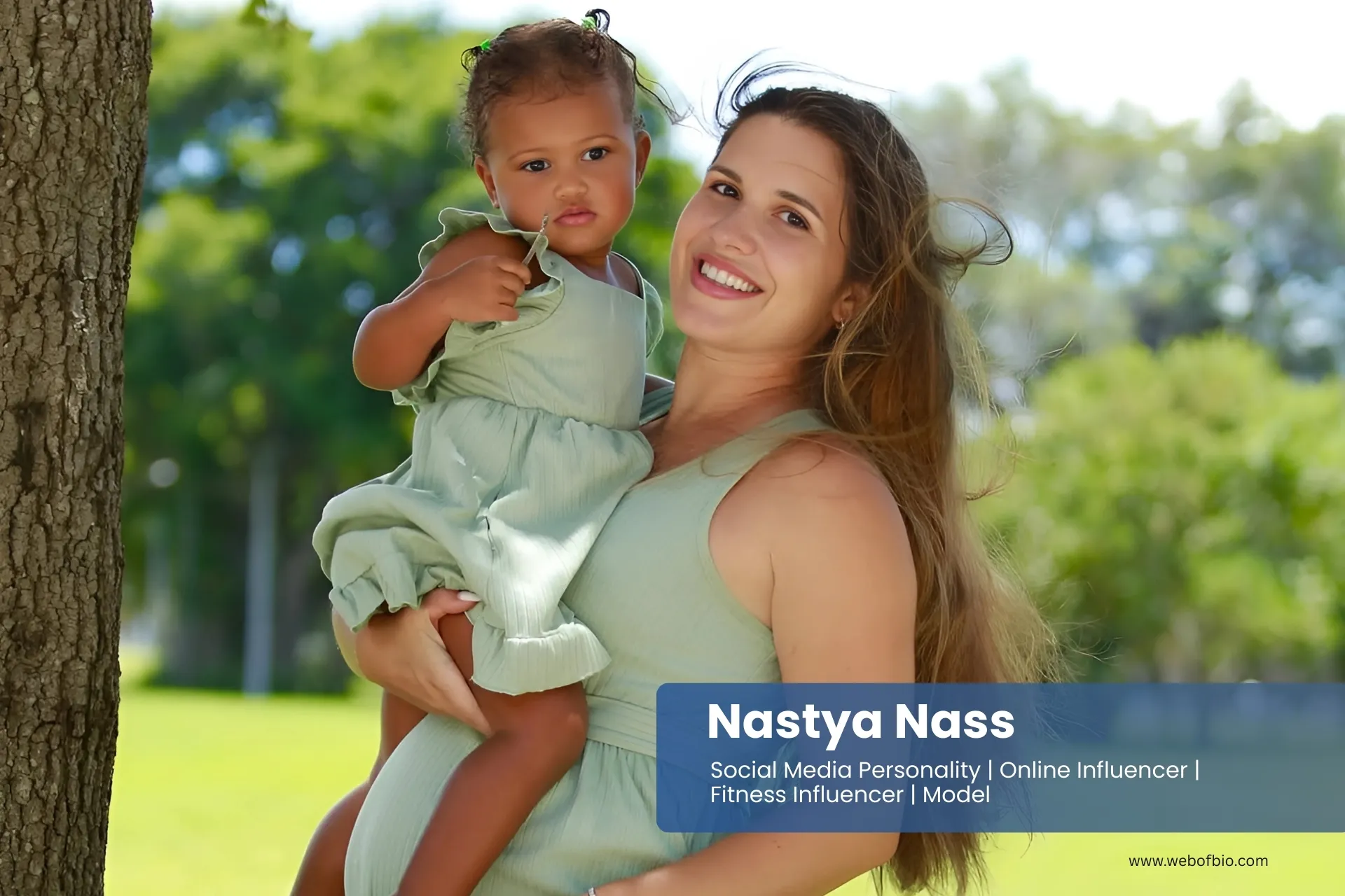 Nastya Nass holding baby in a green dress.