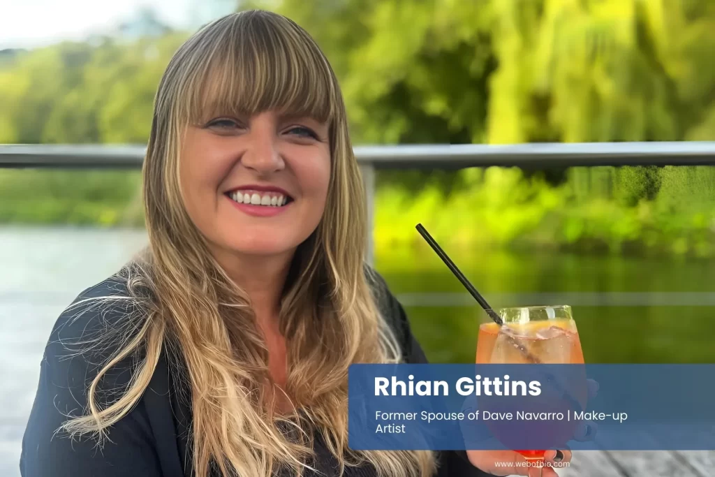 Rhian Gittins sitting at a table, holding a drink with a glass next to her.