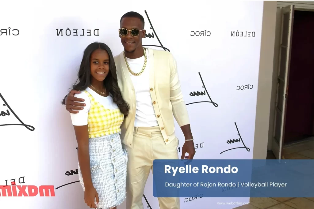 Ryelle Rondo and her father Rajon Rondo standing side by side, smiling, at a formal event with a blurred background of attendees.
