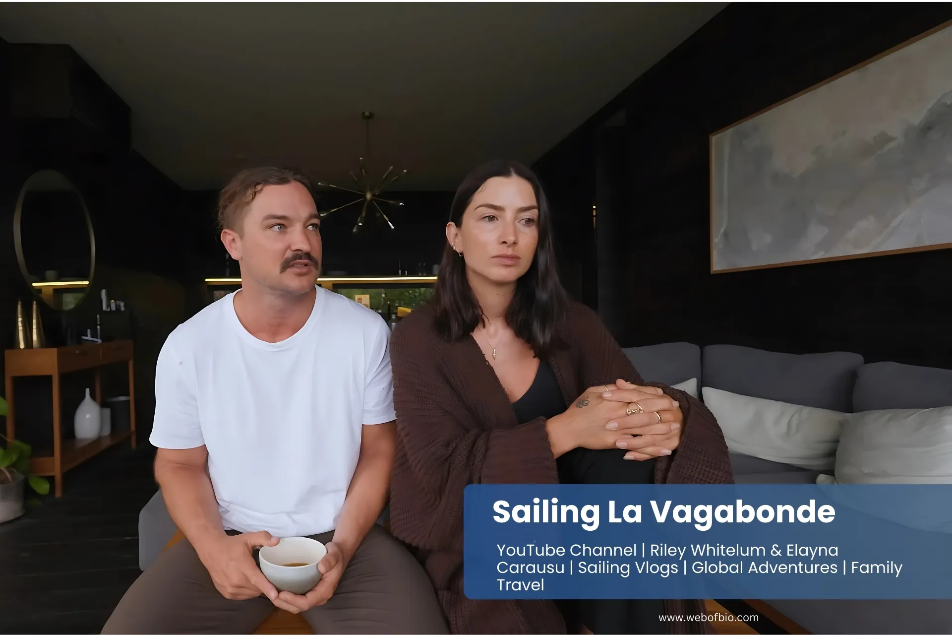 Sailing La Vagabonde sit together on a couch in a cozy living room, engaged in conversation.