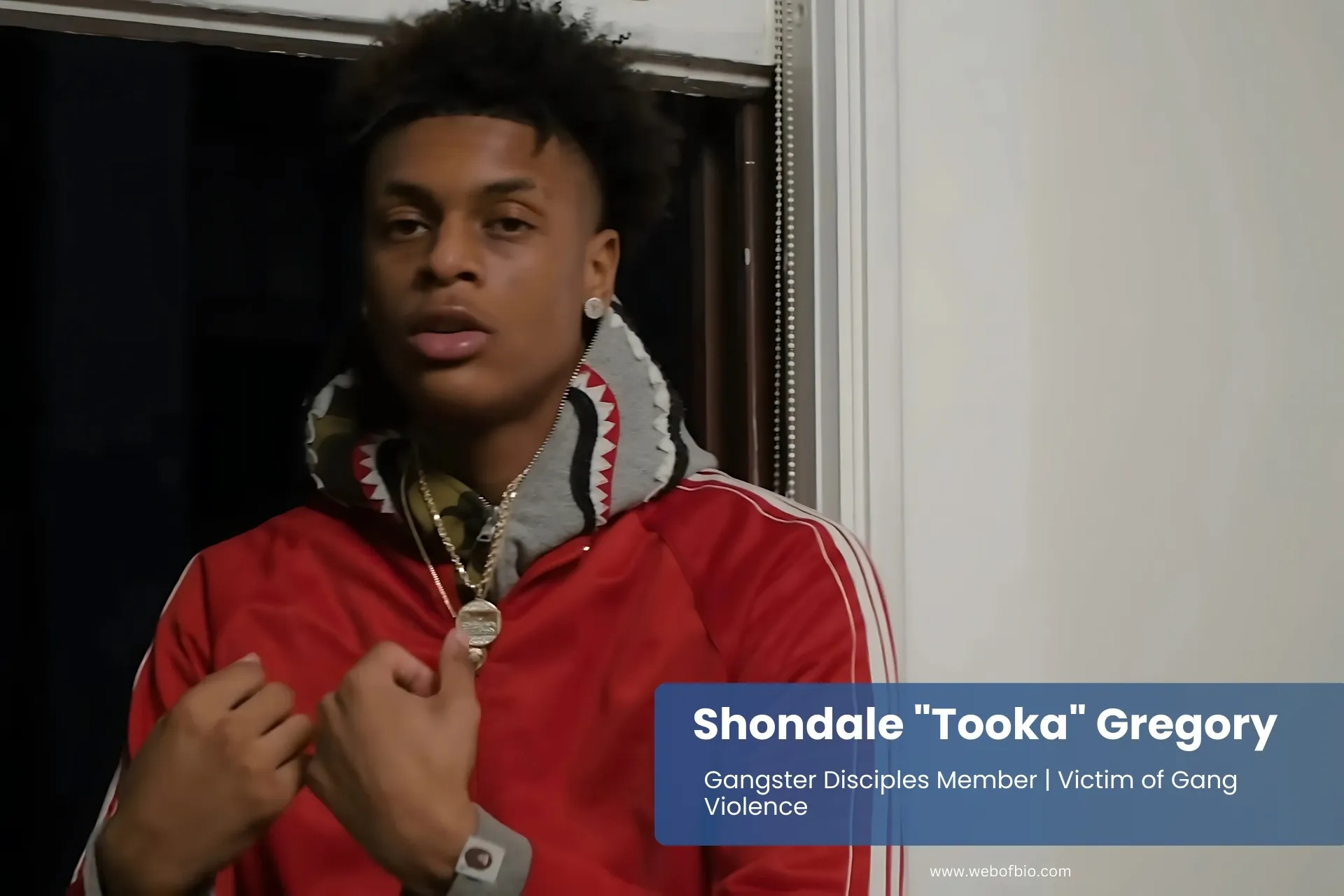 Shondale "Tooka" Gregory in a red jacket standing in front of a window.