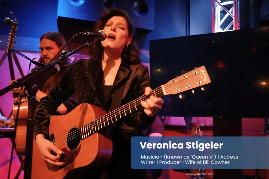 Veronica Stigeler is playing an acoustic guitar in front of a microphone.