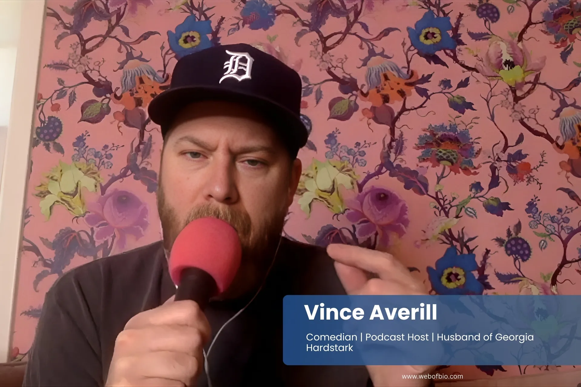 Vince Averill in a baseball cap is talking into a microphone.