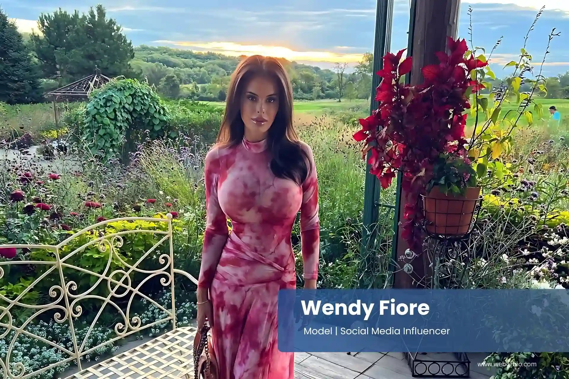 Wendy Fiore in a pink tie dye dress standing on a porch.