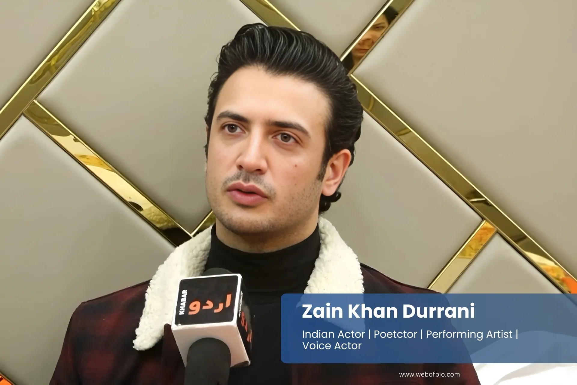 Zain Khan Durrani in a plaid jacket talking to a reporter.