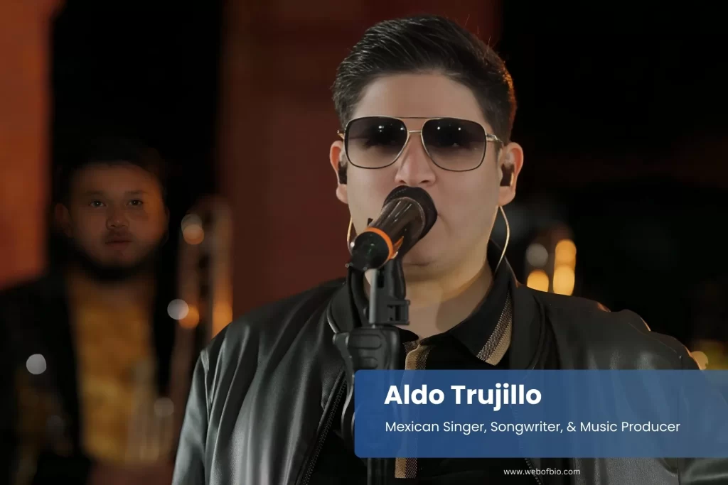 Aldo Trujillo singing into microphone on stage.