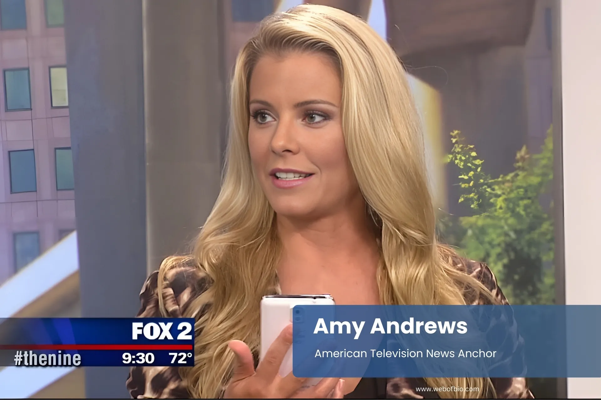Amy Andrews holding cell phone by television.