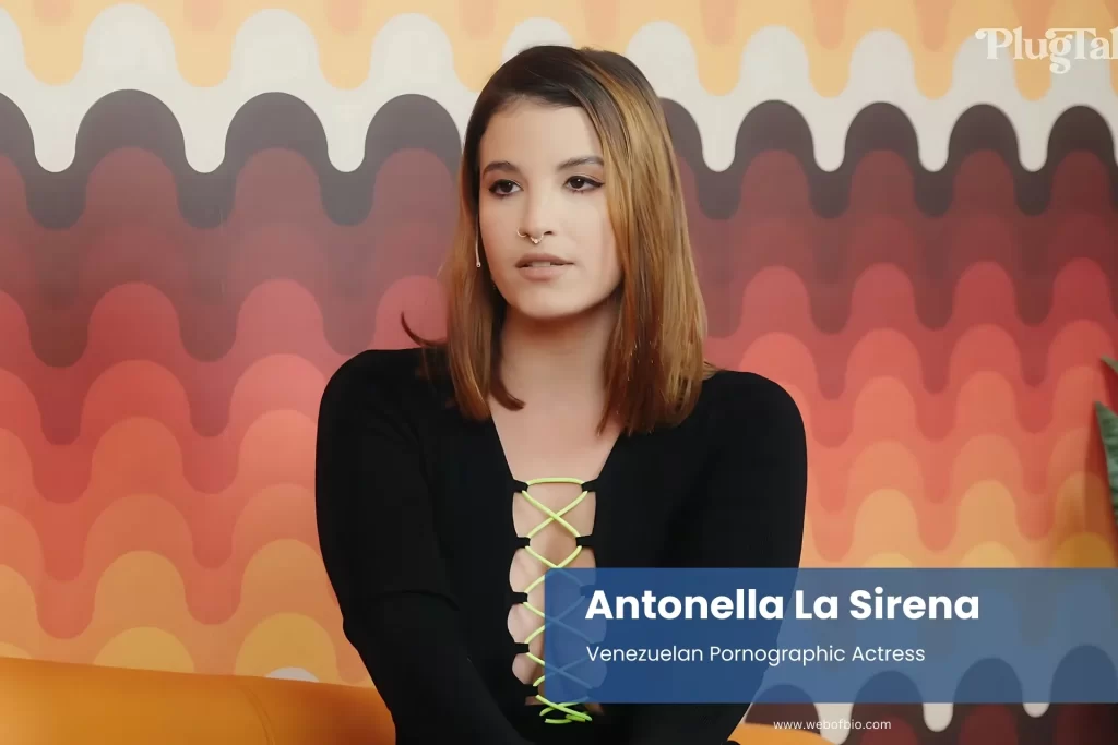 Antonella La Sirena black top on orange couch.