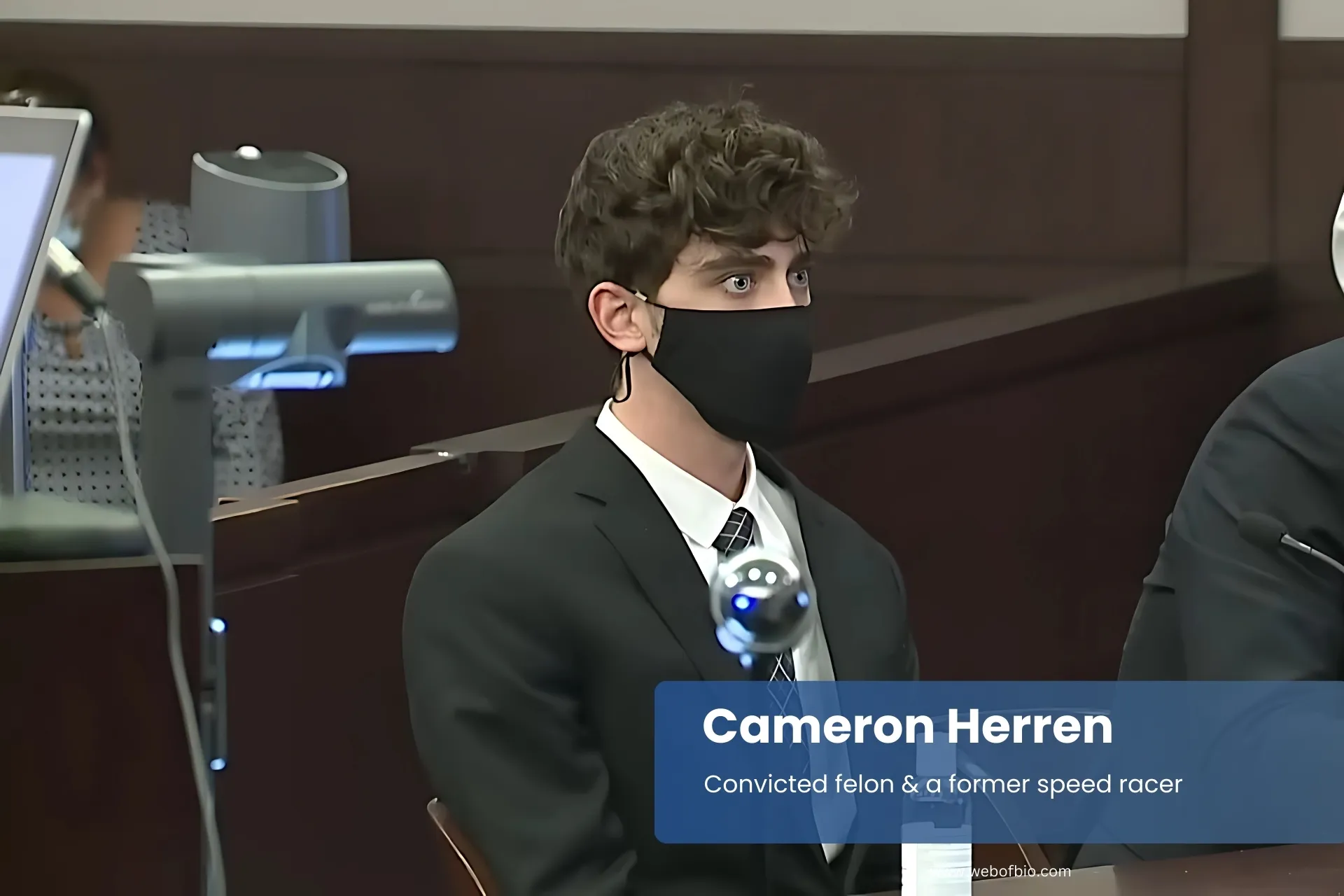 Cameron Herren suits and masks, sitting at table.