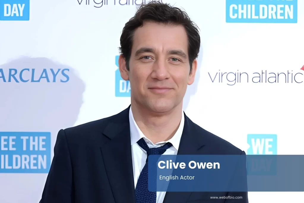 Clive Owen suit and tie on red carpet, standing.