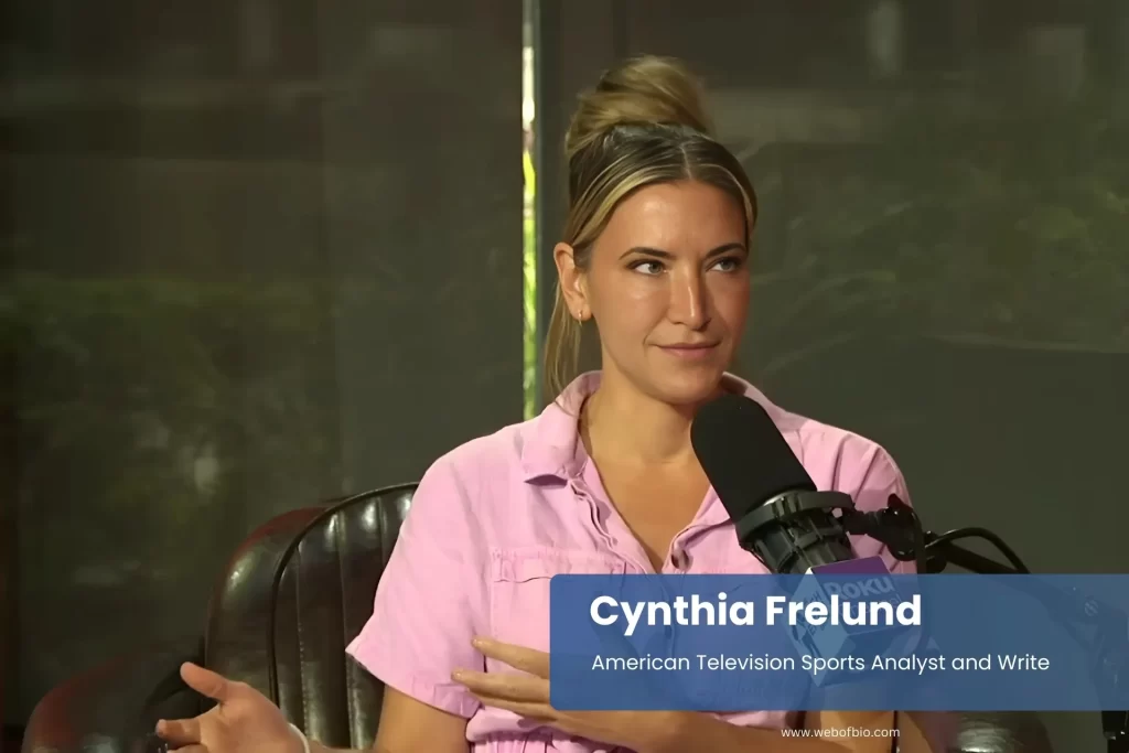 Cynthia Frelund pink shirt, speaking into microphone.