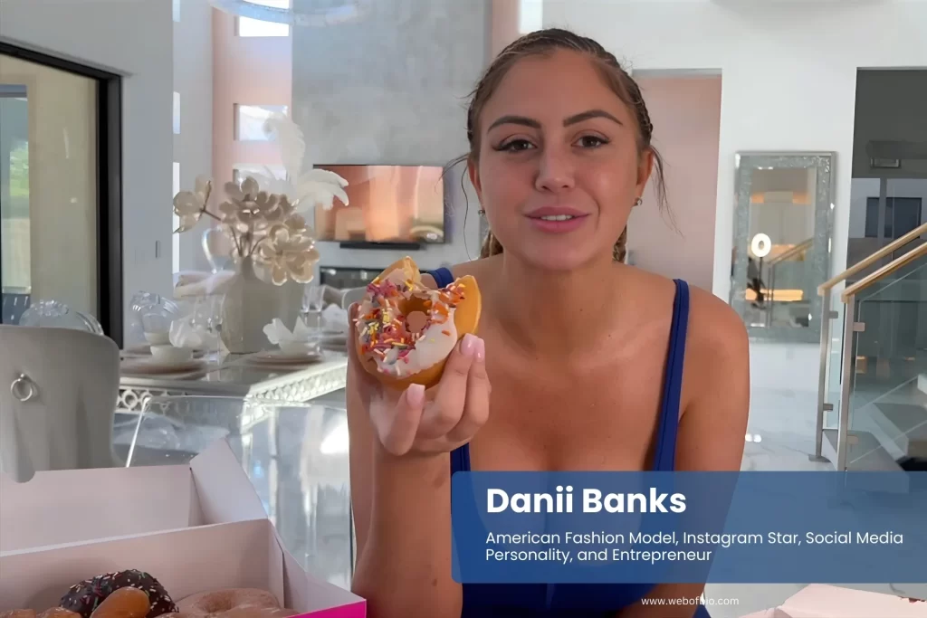 Danii Banks blue top, eating donut, smiling.