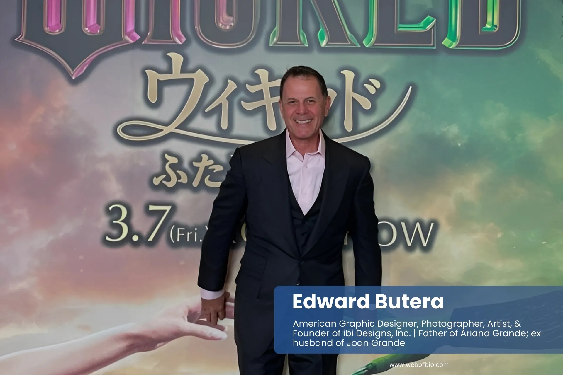 Edward Butera suit, in front of "Wicked" poster.
