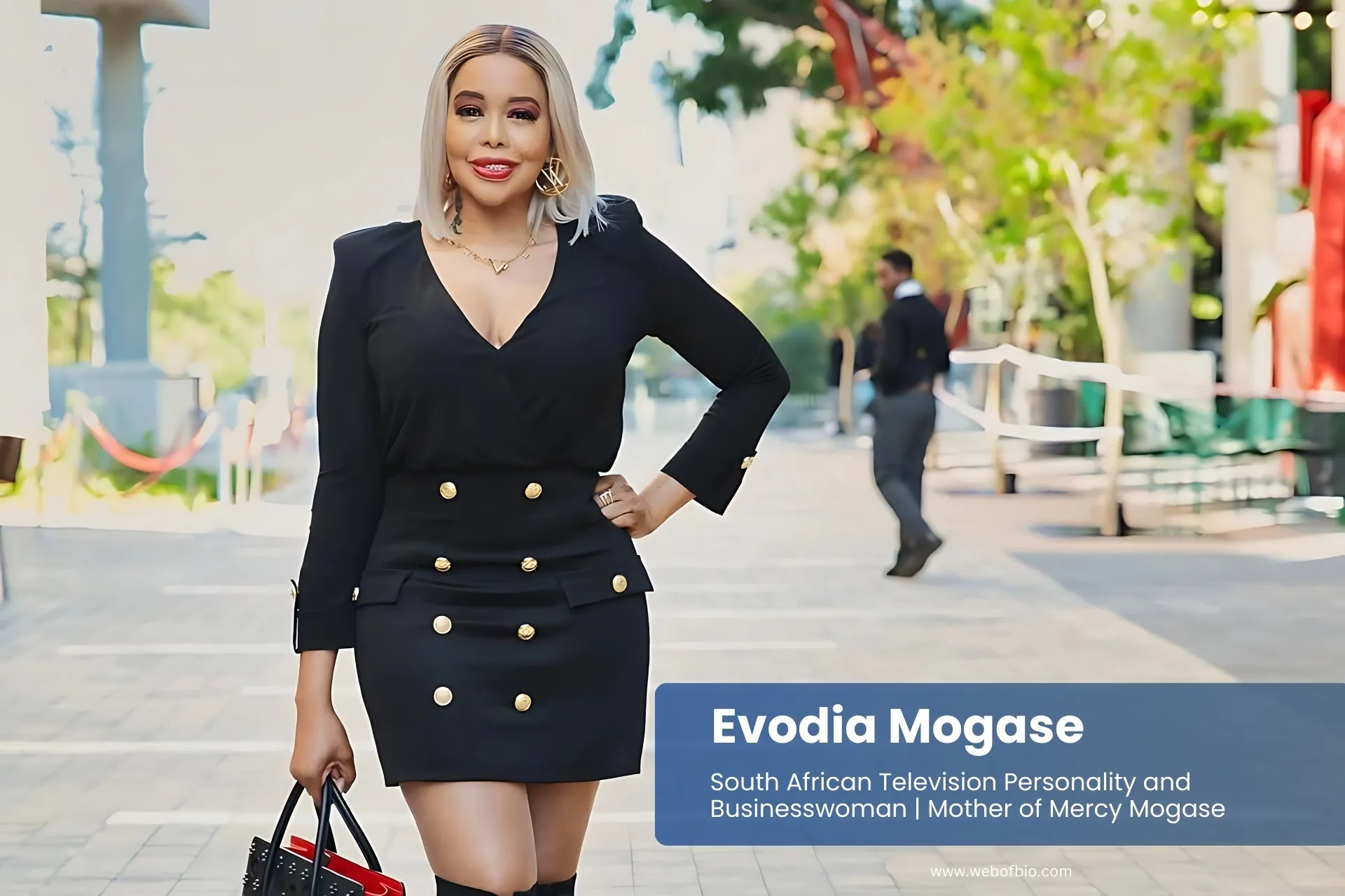 Evodia Mogase black dress and knee-high boots, posing.
