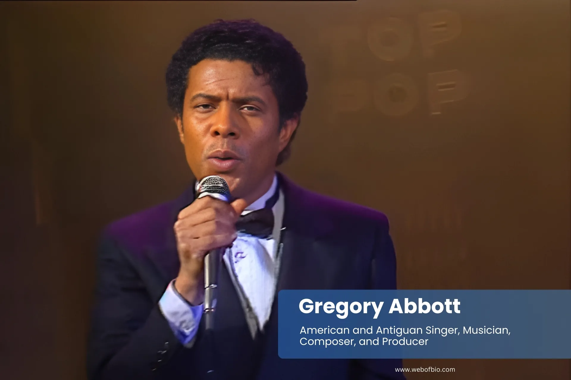 Gregory Abbott suit and tie, singing into microphone.
