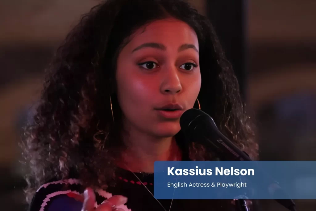 Kassius Nelson singing into microphone on stage.