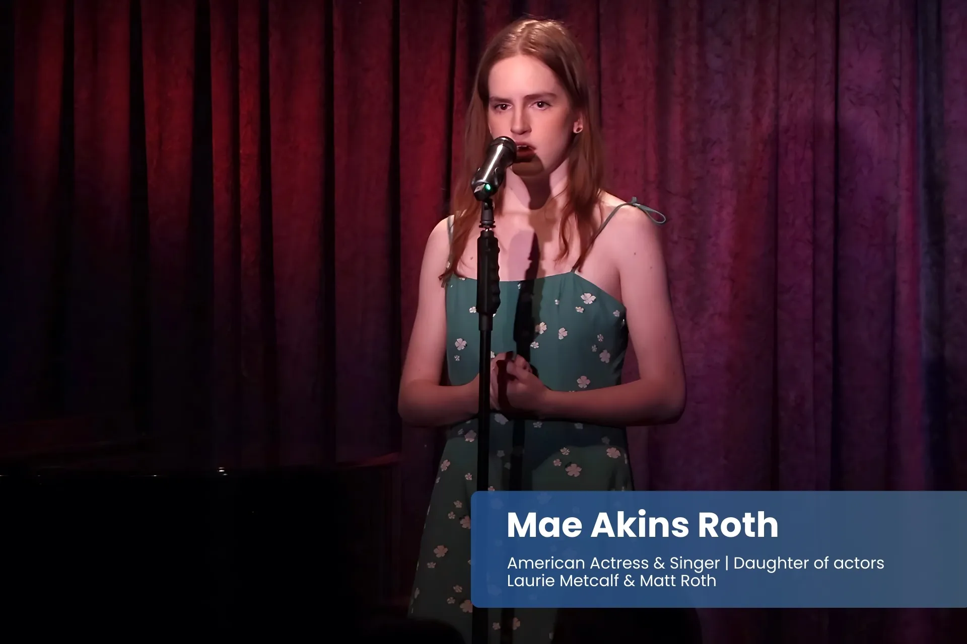 Mae Akins Roth singing into microphone in dress.