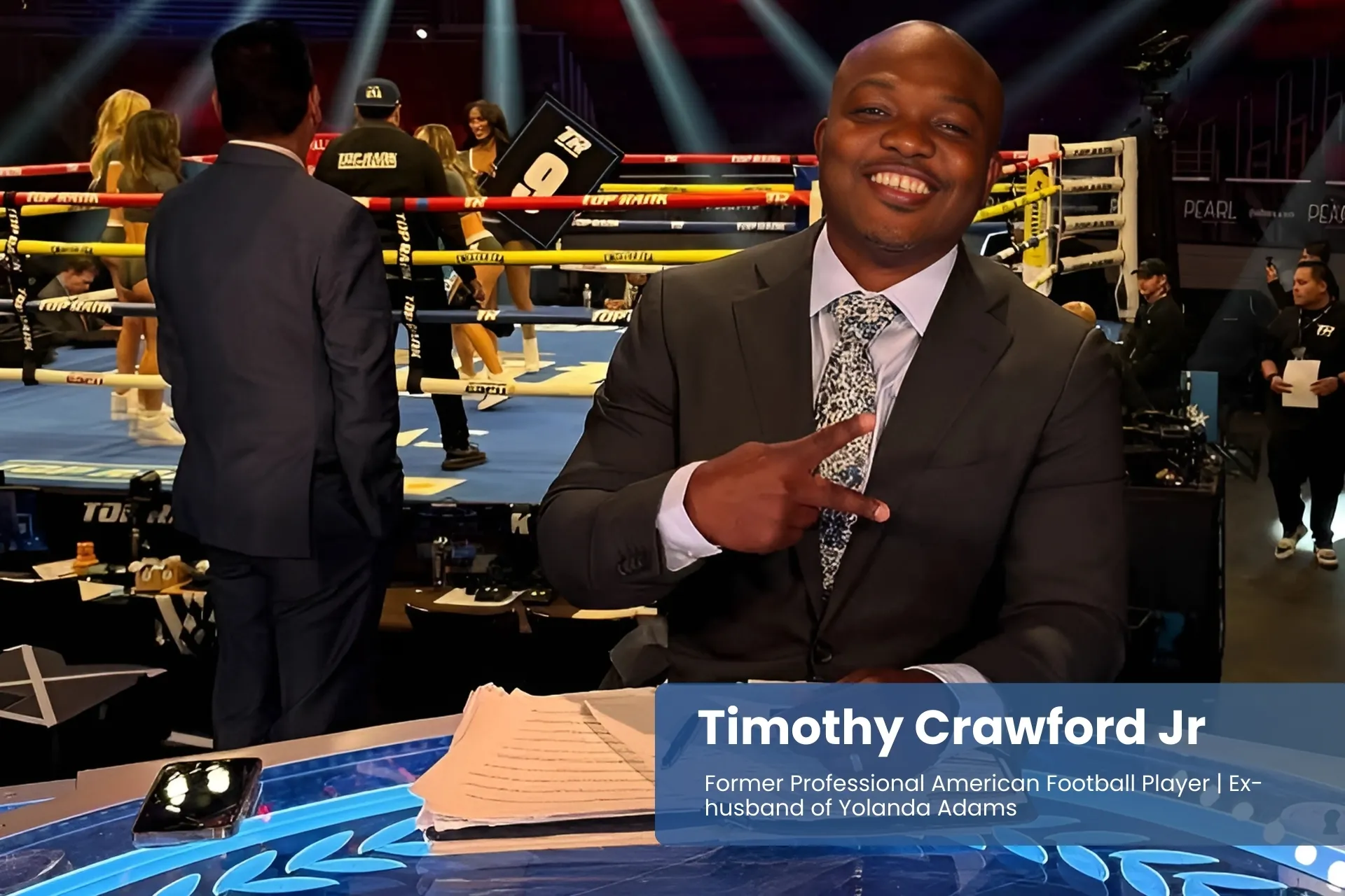 Timothy Crawford Jr. in suit with microphone at table.