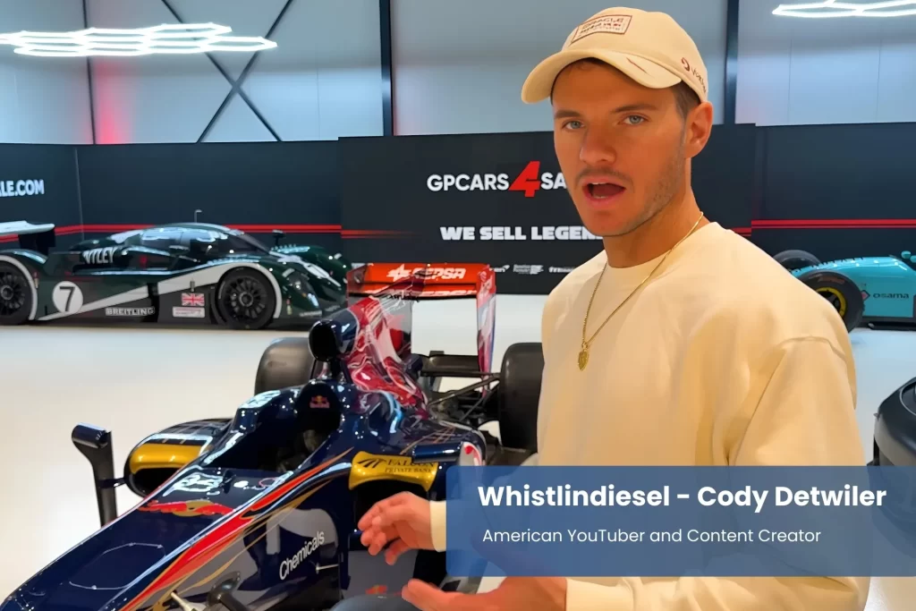 Whistlindiesel posing by race car.